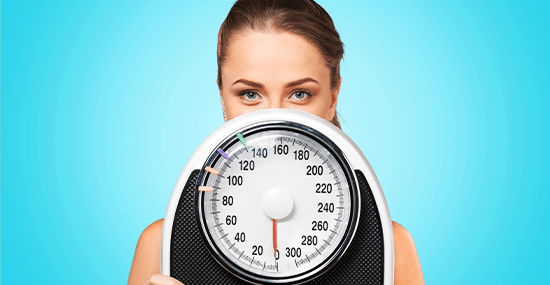 Woman holding a weighing machine in bariatric surgery hospital